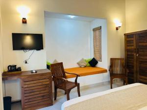 a bedroom with a bed and a desk and a tv at Sekkugala Villa in Koggala