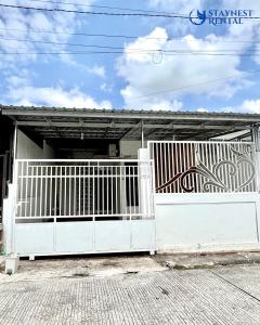 a white gate in front of a white building at House Rental Gajahmada Residence Mataram Lombok in Prampuan
