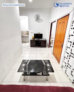 a living room with a glass table on a tiled floor at House Rental Gajahmada Residence Mataram Lombok in Prampuan +3 photos