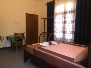 a bedroom with a bed and a chair and a window at Hiri Top Homestay in Dickwella +8 photos