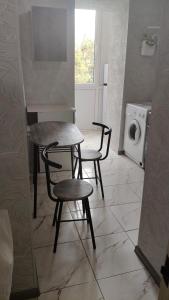 a kitchen with a table and two chairs and a washing machine at Квартира в центре in Mykolaiv