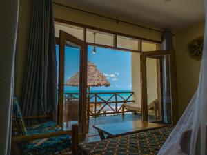 a bedroom with a view of the ocean from a balcony at Mahi Mahi Beach Hotel in Jambiani