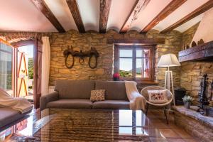 sala de estar con sofá y pared de piedra en Casa Joan de Fontsagrada, en Fontsagrada