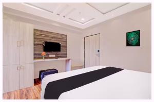 KashiにあるHotel Vivanta Palace Near Vishwanath Templeのベッドとテレビのある白い寝室