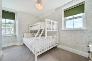 1 dormitorio con 1 litera blanca y 2 ventanas en Perfectly Located, Central Bowness Flat With Free Parking and Lake Views, en Windermere