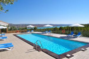 a large swimming pool with chairs and umbrellas at Alojamiento Rural Arucema in Freila