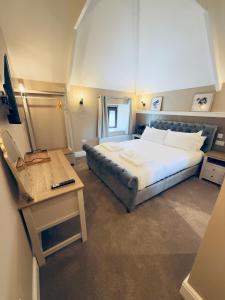 a bedroom with a large bed and a desk with a laptop at Bronn Ewhella - Rising Sun Inn in Altarnun