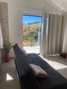 a couch in a living room with a large window at Chalé com café da manhã Rancho Serrapilheira in Munhoz +13 photos