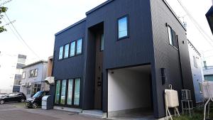 ein blaues Gebäude mit Garage in der Unterkunft HOTELHOUSE Nekogoya Shindohigashi 新道東 in Sapporo