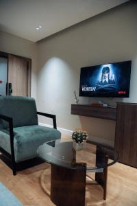 ein Wohnzimmer mit einem grünen Stuhl und einem Flachbild-TV in der Unterkunft Sunny 1-Bedroom with Private Balcony wuse2 in Abuja