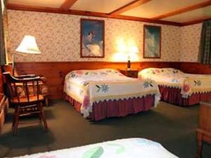 a hotel room with three beds and a chair at White Trellis Motel in North Conway