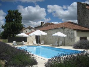 a swimming pool with chairs and umbrellas in front of a house at Val de Costes in Saint-Maurin