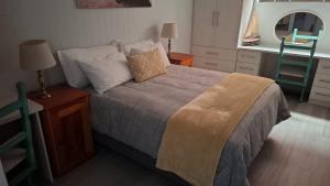 a bedroom with a bed and a table with a chair at Sea Cottage 49 in Mossel Bay