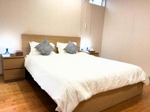une chambre avec un grand lit avec des draps et des oreillers blancs dans l'établissement Riverview唐津, à Karatsu