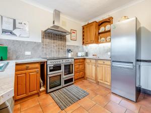 a kitchen with wooden cabinets and stainless steel appliances at Halls Bank Farm in Aspatria