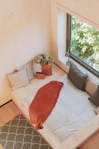 Un sofá sentado en una habitación con ventana. en Die Tinys - Tiny Häuser am Attersee, en Nussdorf am Attersee