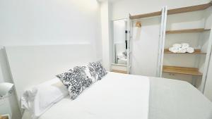 a white bed with a pillow on it in a room at Bajos con encanto by Prestigi in Terrassa