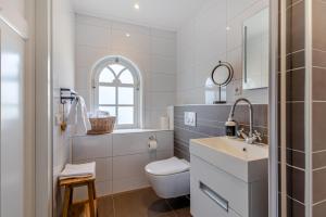 a white bathroom with a toilet and a sink at Luxe B&B Het Rijgebint in Molenaarsgraaf