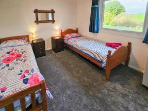 zwei Einzelbetten in einem Zimmer mit Fenster in der Unterkunft Lamastar in Woolfardisworthy