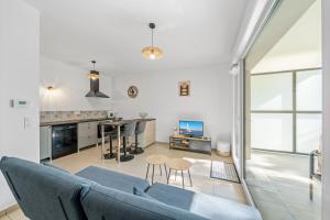 a living room with a blue couch and a kitchen at Le Cocon du Leman in Thonon-les-Bains