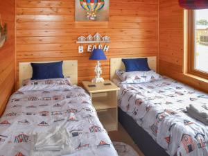 ein Schlafzimmer mit zwei Betten und einem Tisch mit Lampe in der Unterkunft The Dragons Den in Ilfracombe