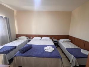 a room with two beds with blue sheets and towels at Pousada Santa Gianna in Aparecida