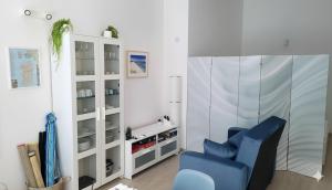 a living room with a blue chair and a white cabinet at La Mandronia Loft in Alghero