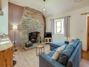 a living room with a blue couch and a fireplace at Thornycroft Cottage in Llanvair Discoed