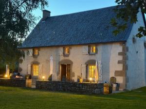 a large white stone house with lights on it at La Maison d'Edouard Spa Chauffé Privé prés du Lac in Lanobre