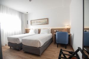 une chambre d'hôtel avec un lit et une chaise bleue dans l'établissement Dazzler by Wyndham Salta, à Salta