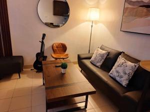 a living room with a couch and a table and a guitar at Hills Residences by JuJu Staycation in Manila +15 photos