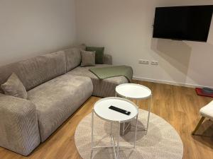 un soggiorno con un divano e due tavoli di Deich-Moment, Apartment 2 auf dem Hundegutshof a Krummendeich