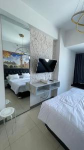 スラバヤにあるLuxury Apartemen Anderson Benson PTC By Staycationのベッド2台と薄型テレビ付きのホテルの部屋