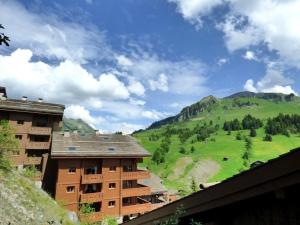 un bâtiment avec vue sur une montagne verdoyante dans l'établissement Confortable 3 pièces au cœur du Chinaillon, 49m² pour 6 personnes, parking inclus - FR-1-458-251, au Chinaillon