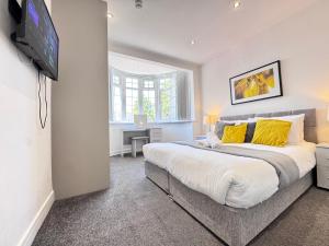 a bedroom with a large bed with yellow pillows at OX London Heathrow stay - 1 BUS to HEATHROW in New Bedfont