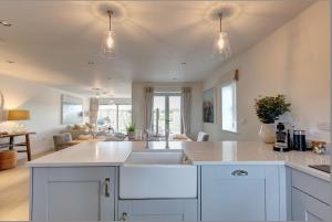a kitchen with white cabinets and a sink at No 1 The Hides Luxury House in North Norfolk in Titchwell