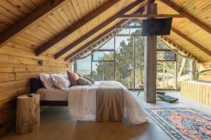 a bedroom with a bed in a room with windows at Chalés do Tabuleiro, Chalé 1 in Palhoça
