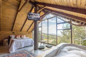 a bedroom with a bed and a large window at Chalés do Tabuleiro, Chalé 1 in Palhoça