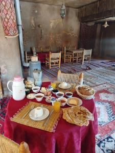 a table with a red table cloth with food on it at Auberge Itrane merzouga in Merzane +55 photos