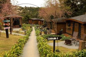 坎波斯杜若尔当Pousada Chales da Mantiqueira - Campos do Jordão的建筑物前的花园里有路牌。