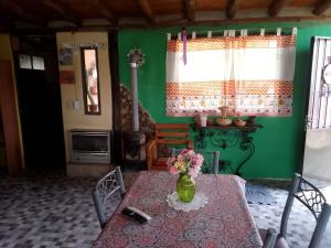 a dining room with a table with a vase of flowers on it at Cabaña Maria y Oscar in Villa Giardino