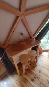 Una mesa de madera y dos taburetes en un ático. en Gîte Insolite La Parenthèse Boisée Aveyron, en Bouillac
