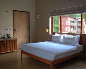 a bedroom with a large bed with a large window at Red River Retreat in Hatikhuli +67 photos