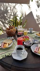 a table topped with plates of food and a cup of coffee at Pousada Casa das Rosas in Búzios