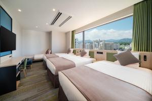 Una habitación de hotel con tres camas y una gran ventana. en HOTEL MYSTAYS Miyazaki, en Miyazaki