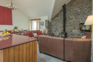 a living room with couches and a stone wall at Deri-Sarn in Sarn