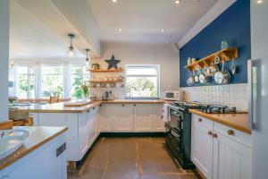 a kitchen with white cabinets and blue walls at Artro in Llanbedr