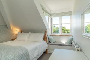 a small bedroom with a bed and two windows at Artro in Llanbedr