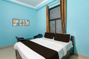 a bedroom with a bed with blue walls and a window at Hotel O Shivam International in Utrāhtia +21 photos