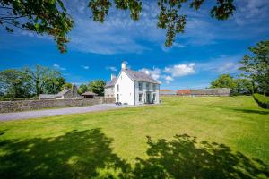 a white house on a grassy field at Hendre-Feinws in Pwllheli